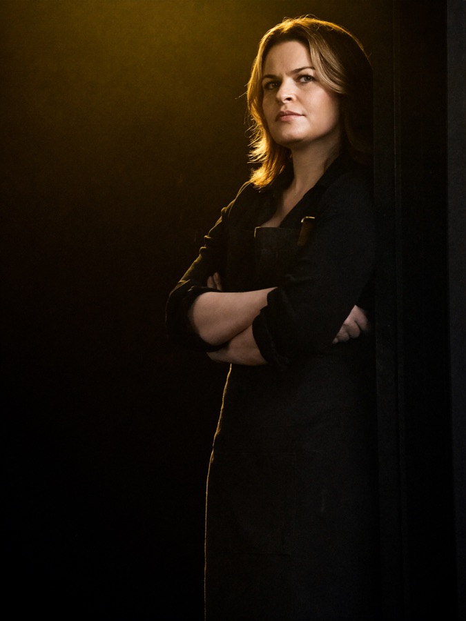 Restaurant owner in the doorway of her restaurant at night